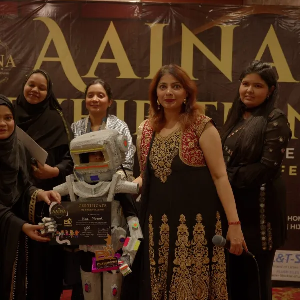 Guests pose with the young robot at AAINA 2026