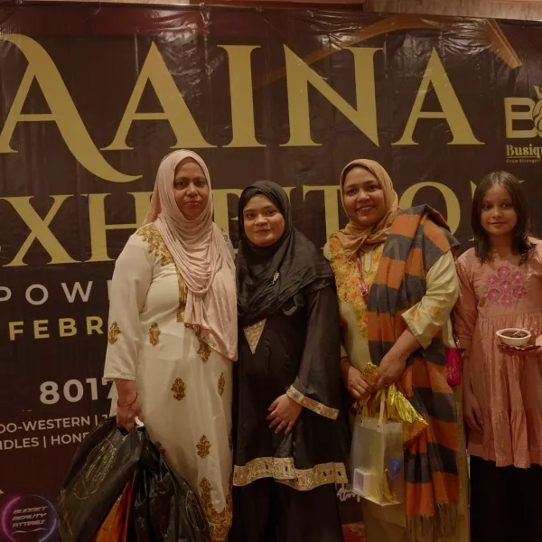 Exhibitors in traditional wear at the AAINA 2026 backdrop